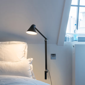NJP wall lamp with long arm and black hardwired mount by Louis Poulsen, modern adjustable wall light with a sleek and functional design